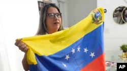 ARCHIVO - La venezolana Yuly Macedo porta una bandera de su país durante una entrevista en Davie, Florida, el jueves 11 de julio de 2024. 