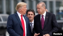 FILE - U.S. President Donald Trump and Turkish President Recep Tayyip Erdogan, right, converse at the start of a NATO summit in Brussels, Belgium, July 11, 2018.