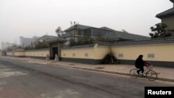 FILE - A man cycles past an unfinished residence which belongs to former People's Liberation Army (PLA) General Gu Junshan, in Puyang, Henan province, Jan. 19, 2014. 