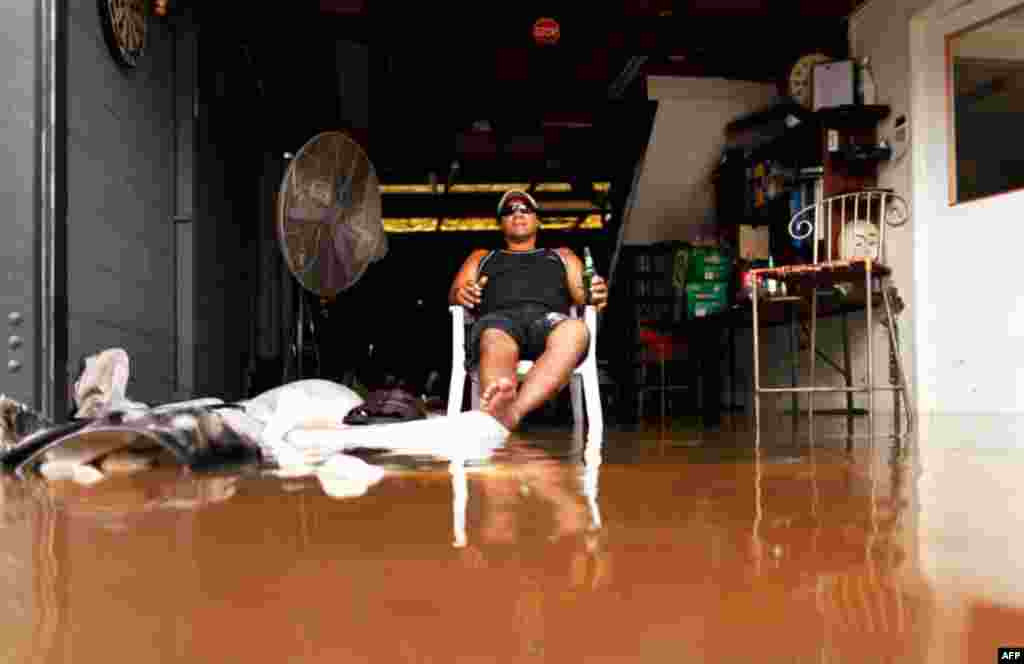 January 13: A man drinks beer as he sits in the entrance to a flooded car repair workshop in Brisbane. Flood water in Australia's third-biggest city peaked below feared catastrophic levels on Thursday but Brisbane and other devastated regions faced years