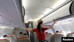 VietJetAir stüardessası Ho Çi Min hava limanında təyyarə havaya qalxmazdan öncə baqajları yoxlayır. Hava yolları şirkəti növbəti ildə təyyarələrin sayını ikiqat artırmaq niyyətindədir.