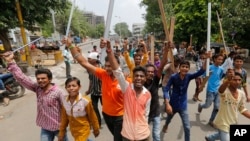 Members of India’s low-caste Dalit community hold wooden sticks and shout slogans in Ahmadabad, India, July 20, 2016. 