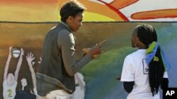 U.S. first lady Michelle Obama, left, paints a mural with youths at Botswana-Baylor Adolescent Center which offers teenagers with HIV support, Gaborone, Botswana, Friday, June 24, 2011