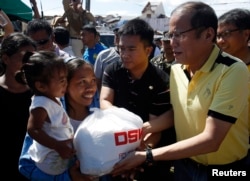 Philippine President Benigno Aquino (R) distributes disaster relief items to survivors of Typhoon Haiyan during his visit to Palo, Leyte province, central Philippines Nov. 18, 2013.