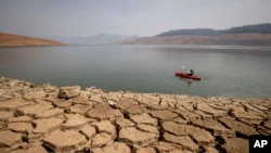 FILE - A kayaker paddles in Lake Oroville as water levels remain low due to continuing drought conditions in Oroville, California, Aug. 22, 2021. 