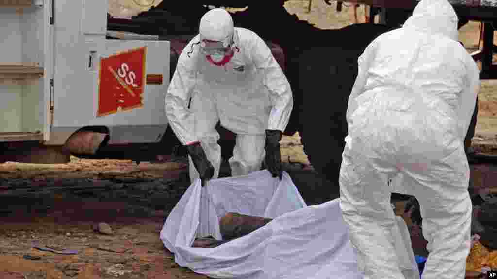 The body of a man found in the street, suspected of dying from the ebola virus is covered and removed by health workers, in Monrovia.