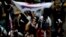 A member of pro-communist union PAME waves a flag outside the Greek state television ERT headquarters during a general strike in Athens, June 13, 2013.