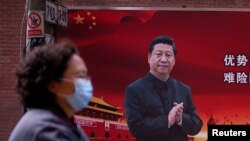 12일 중국 상하이에서 마스크를 쓴 시민이 시진핑 국가주석의 사진 옆을 지나고 있다.