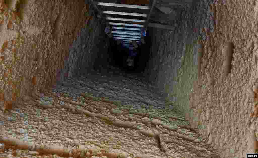 A journalist is seen on the ladder at the entrance to the tombs, during the presentation of a new discovery at Tuna el-Gebel archaeological site in Minya Governorate, Egypt, Feb. 2, 2019.