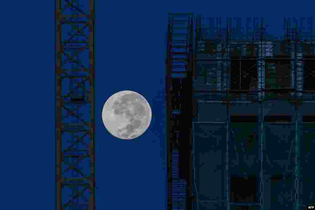 The moon is seen near a construction site in Kuala Lumpur.
