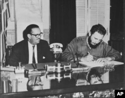 FILE - Cuban Prime Minister Fidel Castro signs decree nationalizing all American-owned banks in Cuba, Sept. 17, 1960.