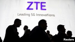 FILE - Visitors pass in front of the Chinese telecoms equipment group ZTE Corp booth at the Mobile World Congress in Barcelona, Spain, Feb. 26, 2018. 