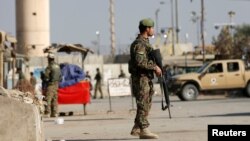 FILE - Afghan National Army soldiers keep watch outside the Bagram Airfield entrance gate, north of Kabul, Nov. 12, 2016. 