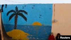 Syrian refugee girls sit in front of a painted wall in the Bab Al-Salam refugee camp in Azaz, near the Syrian-Turkish border, Oct. 27, 2014.
