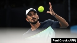 Petenis Lebanon Hady Habib memukul bola melawan petenis China Bu Yunchaokete dalam pertandingan tunggal putra pada hari pertama turnamen Australia Terbuka di Melbourne, 12 Januari 2025. (Foto: Paul Crock/AFP)