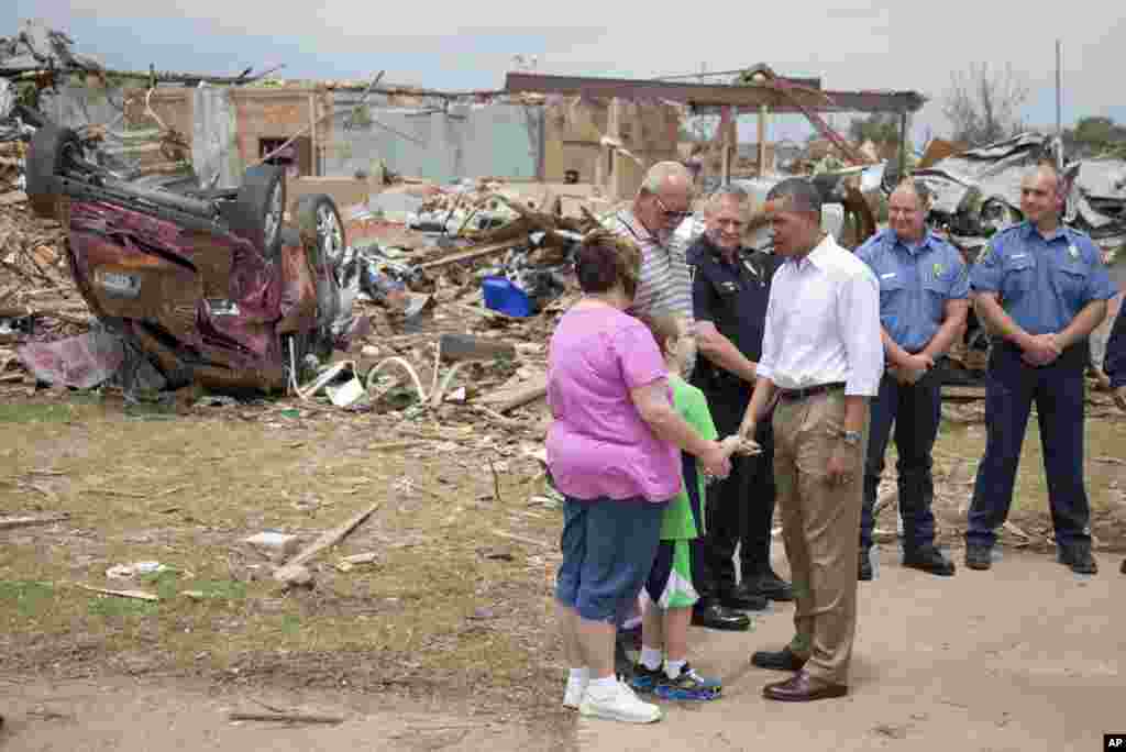 President Barack Obama talks with Julie Lewis, her husband Scott Lewis, and their son Zack, a third-grader at the destroyed Plaza Towers Elementary School seen in the background, Moore, Oklahoma, May 26, 2013.