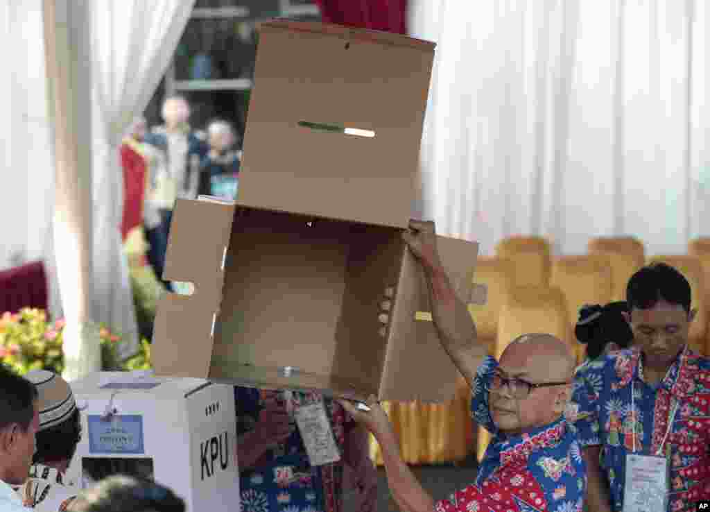 Petugas KPPS menunjukkan kotak suara yang kosong di sebuah TPS di Jakarta, Rabu, 17 April 2019. (Foto: Dita Alangkara/AP)