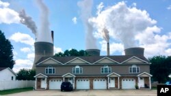  In this Aug. 23, 2018 photo, American Electric Power’s John Amos coal-fired plant in Winfield, West Virginia, is seen from an apartment complex in the town of Poca across the Kanawha River. 
