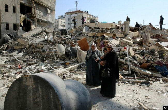 Palestinians search for their family's belongings amid the rubble of destroyed building near a Hamas security building that was destroyed in an Israeli airstrike late Monday, in Gaza City, March 27, 2019.