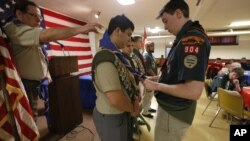 A fellow Eagle scout presents David Fite with his Eagle neckerchief during a ceremony at a Catholic church in Chicago, Jan. 3, 2016, as Fite's scoutmaster, Jerome Lasky, stands behind him.