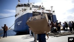 A migrant carries a suitcase after arriving at the port in Benghazi from the besieged Libyan city of Misrata, May 5, 2011