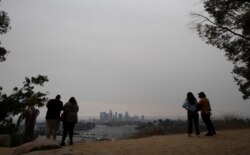 Couples watch downtown from Angels Point at sunset in a smoke haze generated by the Bobcat fire in Los Angeles, California, Sept. 11, 2020.