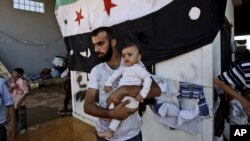 A Syrian man, who fled his home due to government shelling, holds his son as they take refuge at Bab Al-Salameh crossing border, hoping to cross to one of the refugee camps in Turkey, near the Syrian town of Azaz, Sept. 12, 2012. 