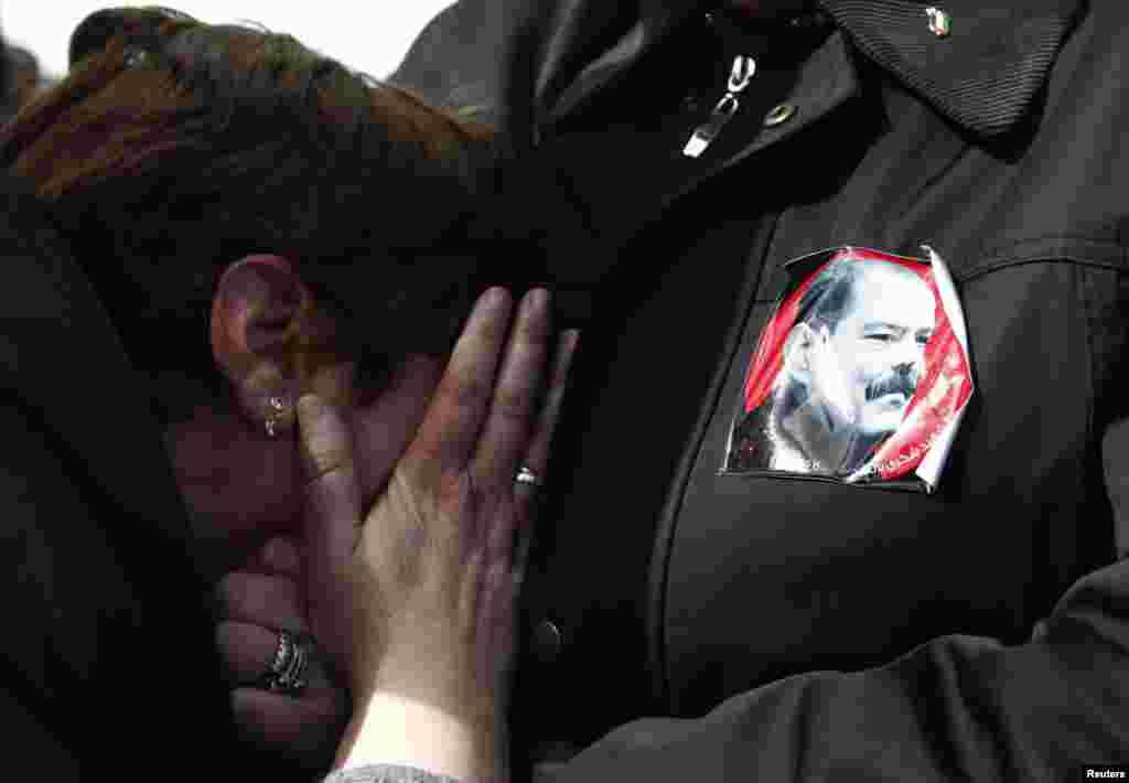 A sticker with an image of the late opposition leader Chokri Belaid is seen as a woman mourns during his funeral procession, Tunis, Feb. 8, 2013.