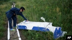 Seorang petugas perairan setempat memeriksa sebuah kepingan pesawat Malaysia Airlines MH17 yang masih tergeletak di lokasi jatuhnya pesawat dekat desa Hrabove, Ukraina timur (14/7).