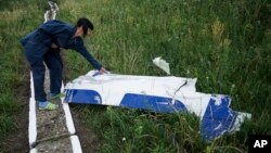 Seorang petugas memeriksa sebuah puing dari pesawat Malaysia Airlines MH17 yang jatuh di sebuah desa di Ukraina timur (foto: dok).