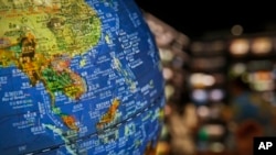 In this July 13, 2018, photo, people read books near a globe showing the southeast countries on the South China Sea with nine-dash line claims under Chinese territory on display at a bookstore in Beijing. 