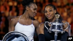 United States' Serena Williams, right, holds her trophy after defeating her sister Venus, left, during the women's singles final at the Australian Open tennis championships in Melbourne, Australia, Jan. 28, 2017.