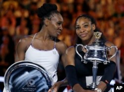 United States' Serena Williams, right, holds her trophy after defeating her sister Venus, left, during the women's singles final at the Australian Open tennis championships in Melbourne, Australia, Jan. 28, 2017.