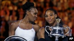 Bintang tenis putri Amerika, Serena Williams, (kanan) memegang piala kemenangannya setelah mengalahkan kakaknya, Venus (kiri) dalam Final Kejuaraan Tenis Australian Open di Melbourne, Australia, 28 Januari 2017. (AP Photo/Aaron Favila) 