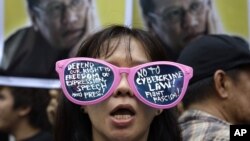 A protester, wearing sunglasses with slogans, stands in front of picture of Philippine President Benigno Aquino III during a rally against the anti-cybercrime law in front of the Supreme Court in Manila, Philippines, October 9, 2012. 