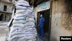 A medic stands behind sandbags in the damaged al-Hakeem hospital, in the rebel-held besieged area of Aleppo, Syria, Nov. 19, 2016. Top U.N. officials warned Monday, Nov. 21, 2016, that health care services in Syria have been devastated by bombings.