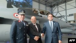 De la gauche, le général-major Ragaa Rabie Youssef de la force aérienne, le chef de Dassault Aviation, Eric Trappier et l’ambassadeur de l’Egypte en France, debout près d’un avion de chasse Rafale, échange une poignée de mains à Istres. France, 20 juillet
