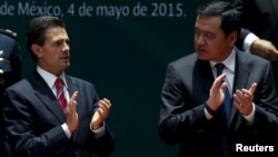 Mexico's President Enrique Pena Nieto (L) applauds with Mexico Interior Minister Miguel Angel Osorio Chong during a ceremony to sign into law a new-anti corruption legislation, at the National Palace in Mexico City, May 4, 2015. 