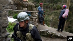 Self-defense members standing guard, top, talk as a soldier patrols outside a school that will be used as a polling station in Uchuraccay, Peru, April 9, 2016. Peruvians head to the ballot box for general elections on Sunday.