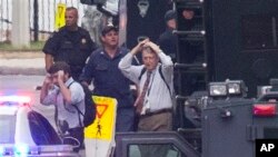 People hold their hands to their heads as they are escorted out of the building where a deadly shooting rampage occurred at the Washington Navy Yard, Sept. 16, 2013.
