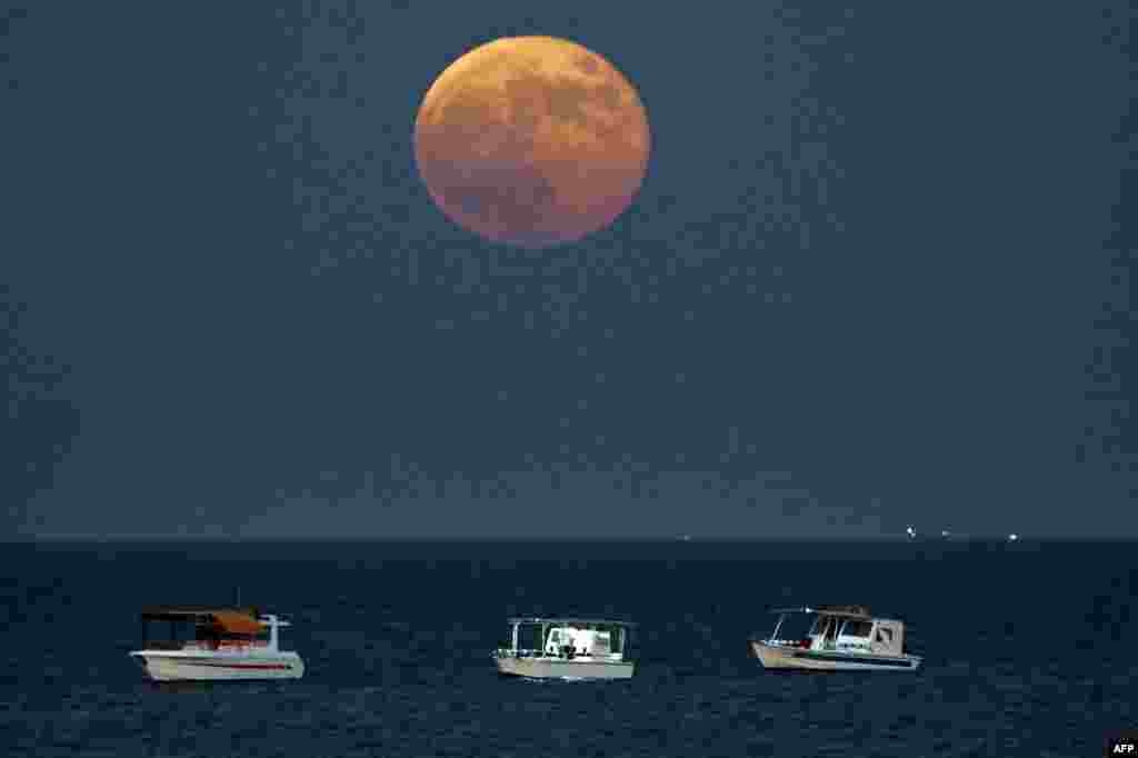 Los barcos pesqueros navegan mientras la superluna llena &quot;de la cosecha&quot; se eleva sobre las aguas del Golfo frente a la costa de la ciudad de Kuwait el 18 de septiembre 2024. &nbsp;