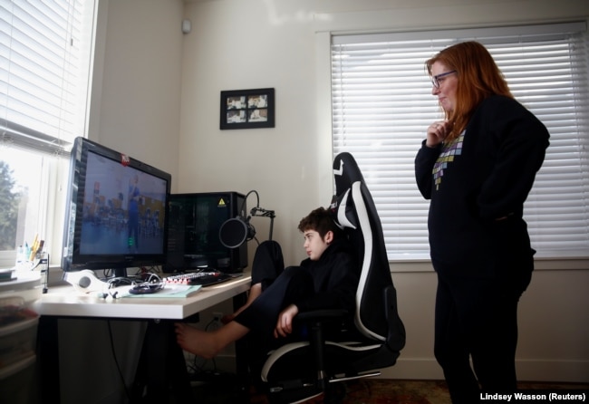 Tracey Pucci and son Foxton Harding, 12, watch an exercise video created by Foxton's teachers at Northshore Middle School as the school district moves to online learning for two weeks because of the new coronavirus, March 11, 2020. (Photo: Reuters / Lindsey Wassen)