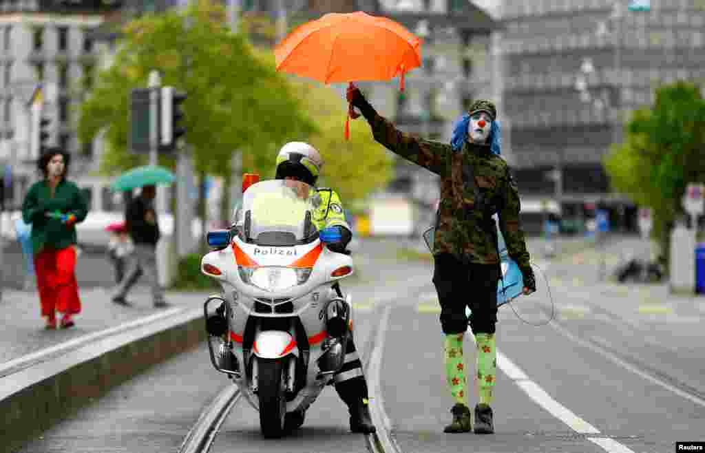 스위스 취리히에서 진행된 노동절 집회 도중 광대복장을 한 시위대원이 경찰관에게 우산을 씌워주고 있다.