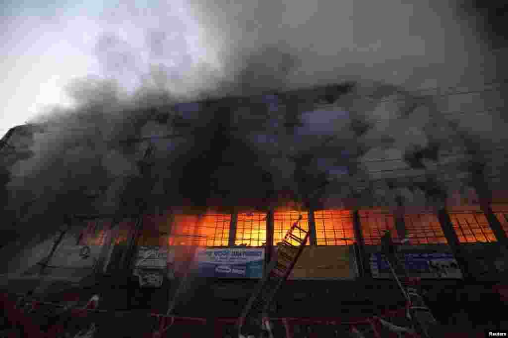 Locals and fire-fighters try to control a fire at a garment factory in Dhaka, Bangladesh. But no one was in the building at the time of fire and there were no casualties, a police official said.