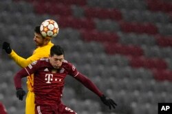 Dan wasan Bayern Robert Lewandowski, na gaba, da Gerard Pique na Barcelona sun tsallake rijiya da baya yayin wasan kwallon kafa na gasar zakarun Turai a rukunin E tsakanin Bayern Munich da FC Barcelona a Munich, Jamus, Laraba, 8 ga Disamba, 2021. (AP Phot