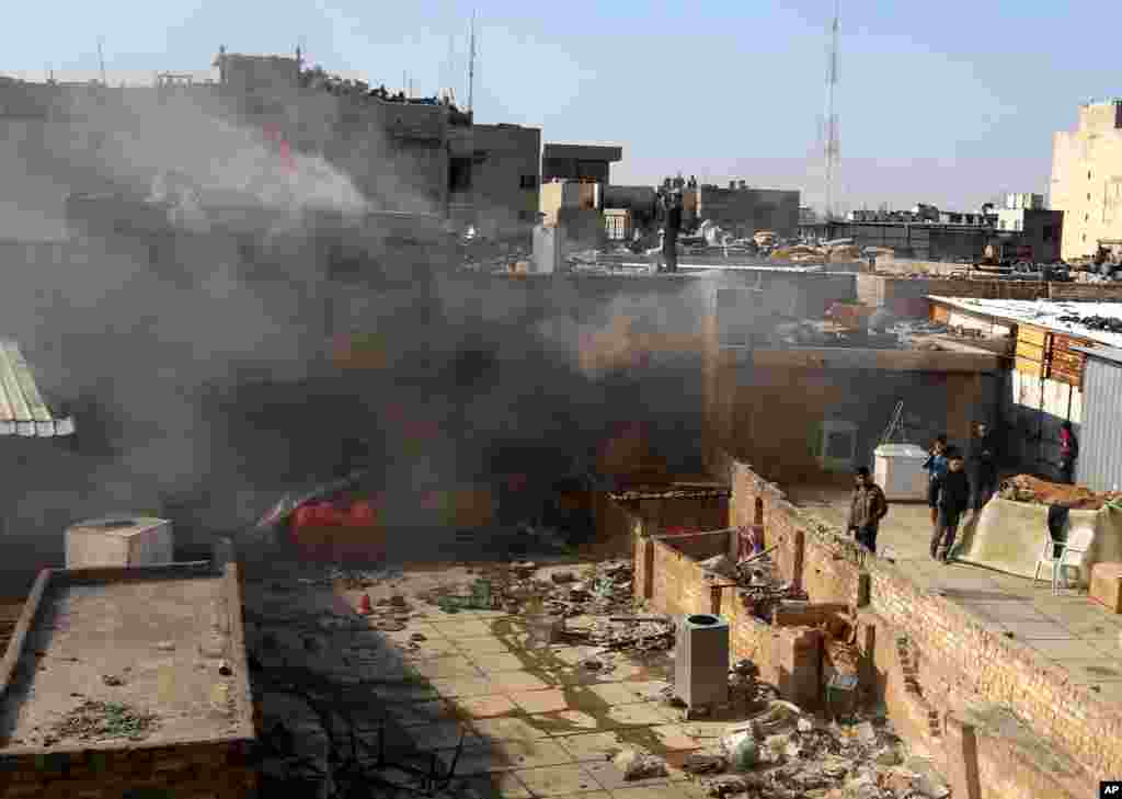 Civilians inspect the site of a car bomb attack at a commercial center in Khilani Square in central Baghdad, Feb. 5, 2014.