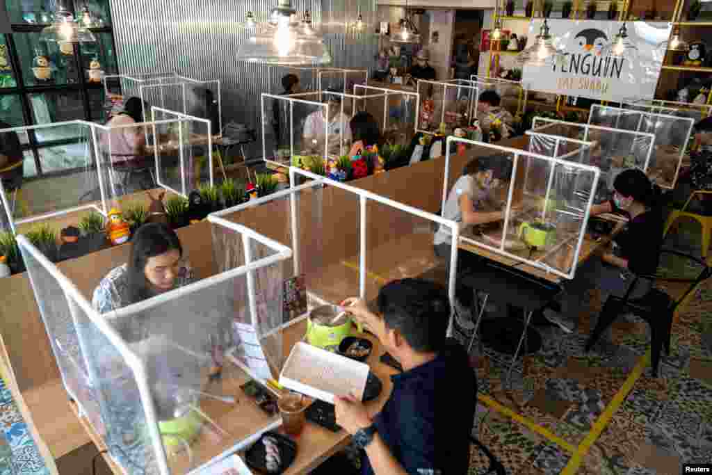 People have lunch at the Penguin Eat Shabu hotpot restaurant that reopened with the implementation of a plastic barrier and social distancing measures to prevent the spread of the coronavirus disease in Bangkok, Thailand, May 8, 2020. REUTERS/Athit Perawo