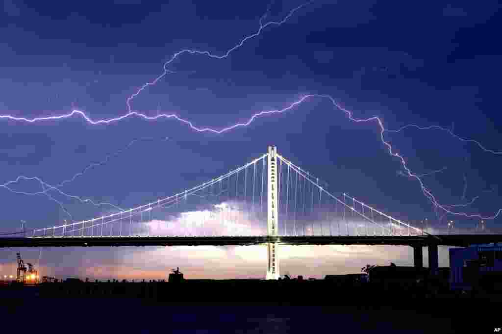 Lightning forks over the San Francisco-Oakland Bay Bridge as a storm passes over Oakland, California.