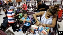 Immigrant Elyse Hernandez, from Honduras, right, waits with her daughter Genesis, center, and son, Jorge David, left, inside the bus station Saturday, June 23, 2018, in McAllen, Texas. (AP Photo/David J. Phillip)
