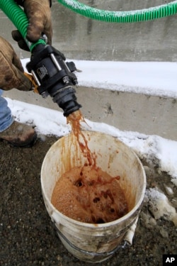 In a demonstration, a bucket is filled with beet juice at the Pennsylvania Department of Transportation's Butler, Pa., maintenance facility, Jan. 6, 2014, which is then mixed with road rock salt that is largely ineffective below 16 degrees.